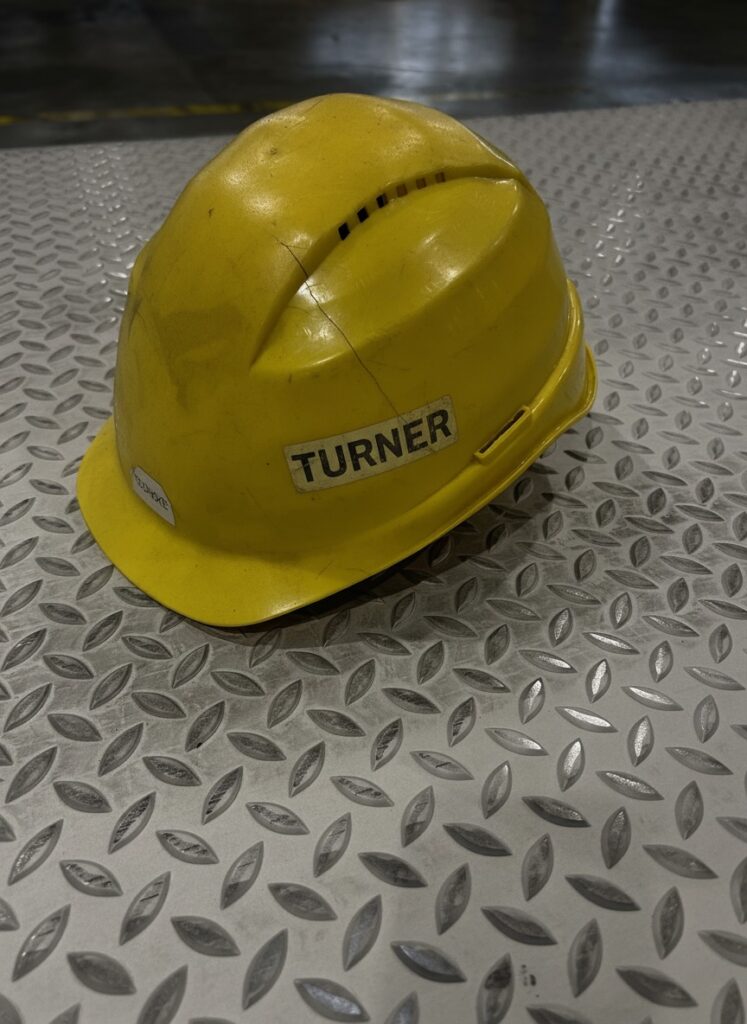 Arbeitshelm mit der Aufschrift TURNER auf Metallboden